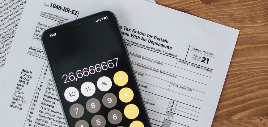 tax forms with calculator with coins on wooden surface