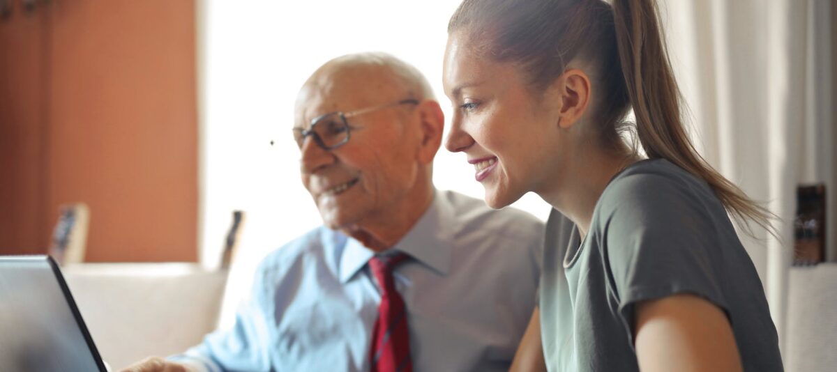 young woman helping senior man with payment on internet using laptop